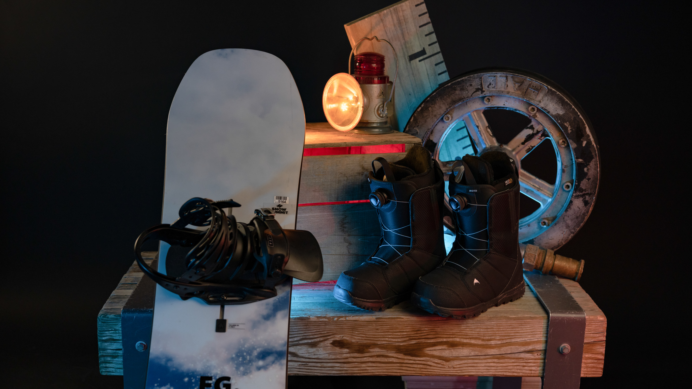 Snowboard with bindings and boots displayed against wooden box